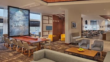 A spacious lobby with a large wooden table and chairs, a seating area with sofas, and a large artwork on the wall.