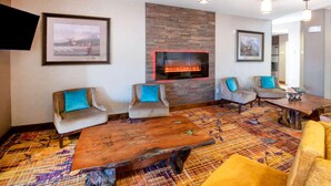 A modern lounge area with a fireplace, comfortable seating, and a patterned carpet. - La Quinta Inn & Suites by Wyndham Durango (Durango)