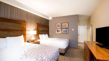 A hotel room with two beds, a TV, a desk, and a door leading to a bathroom.