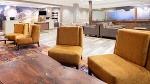 A lobby with a reception desk, seating area, and a large mural. - La Quinta Inn & Suites by Wyndham Durango (Durango)