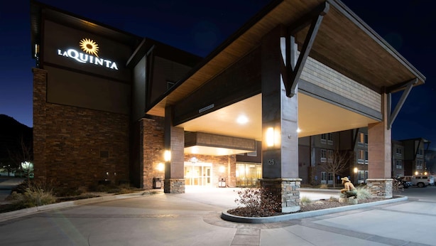 A hotel entrance with a prominent sign, a covered walkway, and a landscaped area with plants. - La Quinta Inn & Suites by Wyndham Durango (Durango)