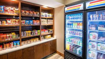 A snack and beverage display area with shelves stocked with various snacks and a refrigerated section with bottled water and sodas.