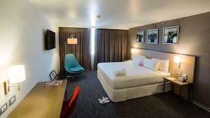 A hotel room with a bed, a desk, a chair, a lamp, a nightstand, and a wall-mounted TV. - Tierra Viva Tacna (Tacna)
