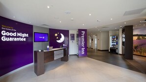 En hotellobby med en skylt som utlovar en "god natts sömn", en receptionsdisk, en tv och en skylt med texten "Premier Inn".