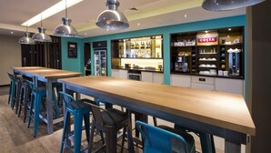 Een bar met krukken, een toog en een bord waarop 'COSTA' staat.