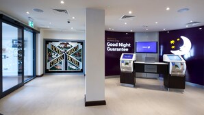 Zona d'eixida d'un hotel, amb un cartell de 'Good Night Guarantee', una taula d'eixida i un quiosc d'enregistrament.