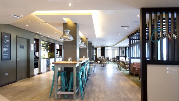 Un vestíbul d'hotel modern amb una zona de bar, seients i una taquilla.