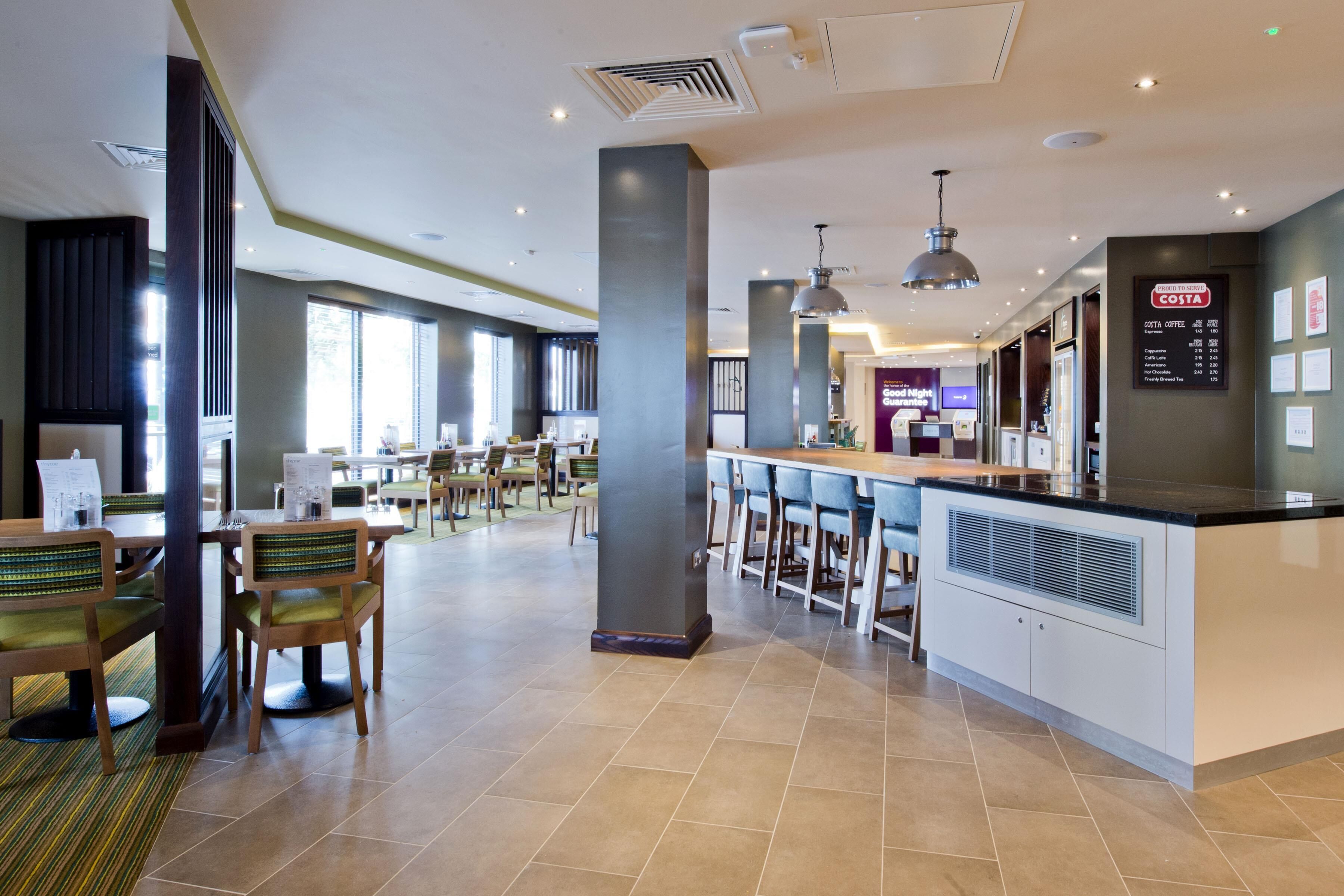 A modern restaurant with high tables, chairs, and a bar area.