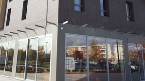 Un bâtiment moderne, doté d’une enseigne verte bien visible, de grandes fenêtres et surplombant un ciel dégagé.