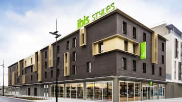 Un moderno edificio di un hotel con un'insegna verde ben visibile con la scritta 'ibis styles'.