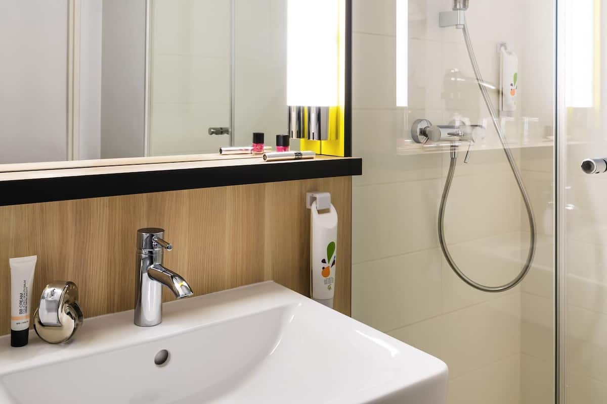 Une salle de bain avec un lavabo blanc, un robinet chromé et une douche à parois en verre.