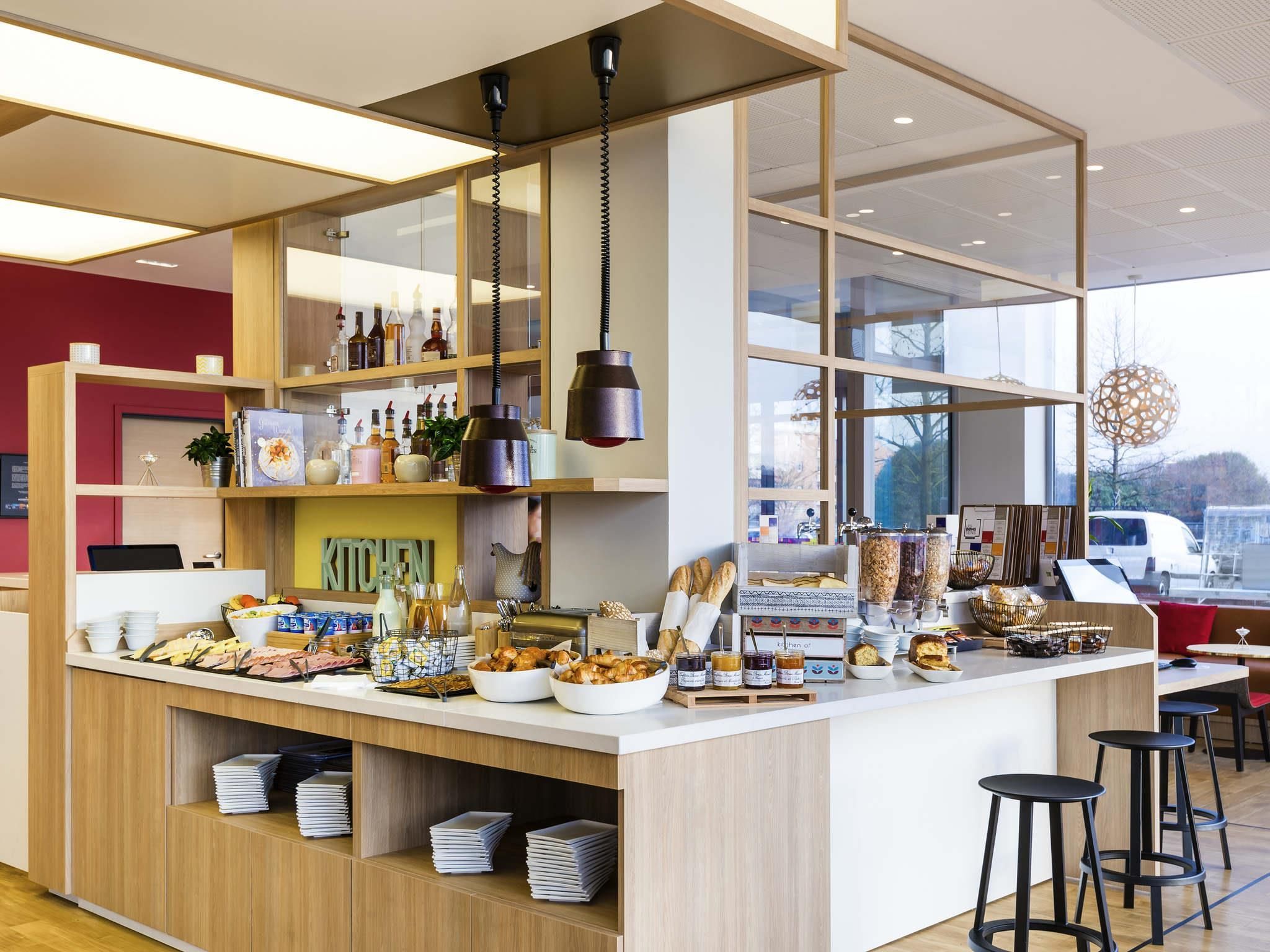 Un espace cuisine moderne avec un comptoir où sont exposés divers produits alimentaires, un ordinateur portable et une pancarte indiquant « CUISINE ».
