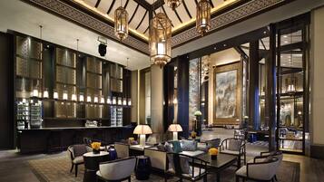 A bar area with seating, a chandelier, and a large painting.
