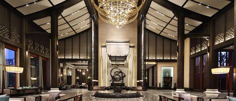 A spacious lobby with a large chandelier, seating areas, and a central decorative piece.