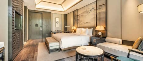 Una habitación de hotel moderna con una cama grande, un sofá, una mesita redonda y un escritorio.