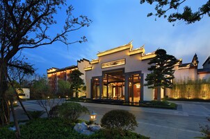 A traditional building with a modern entrance, surrounded by greenery and a well-maintained garden.