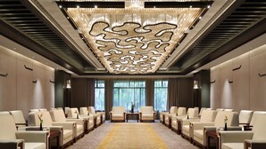 A hotel lobby with rows of seating, a patterned carpet, and a decorative ceiling.