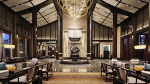 A spacious lobby with a large chandelier, seating areas, and a central decorative piece.