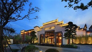 A traditional building with a modern entrance, surrounded by greenery and a well-maintained garden.