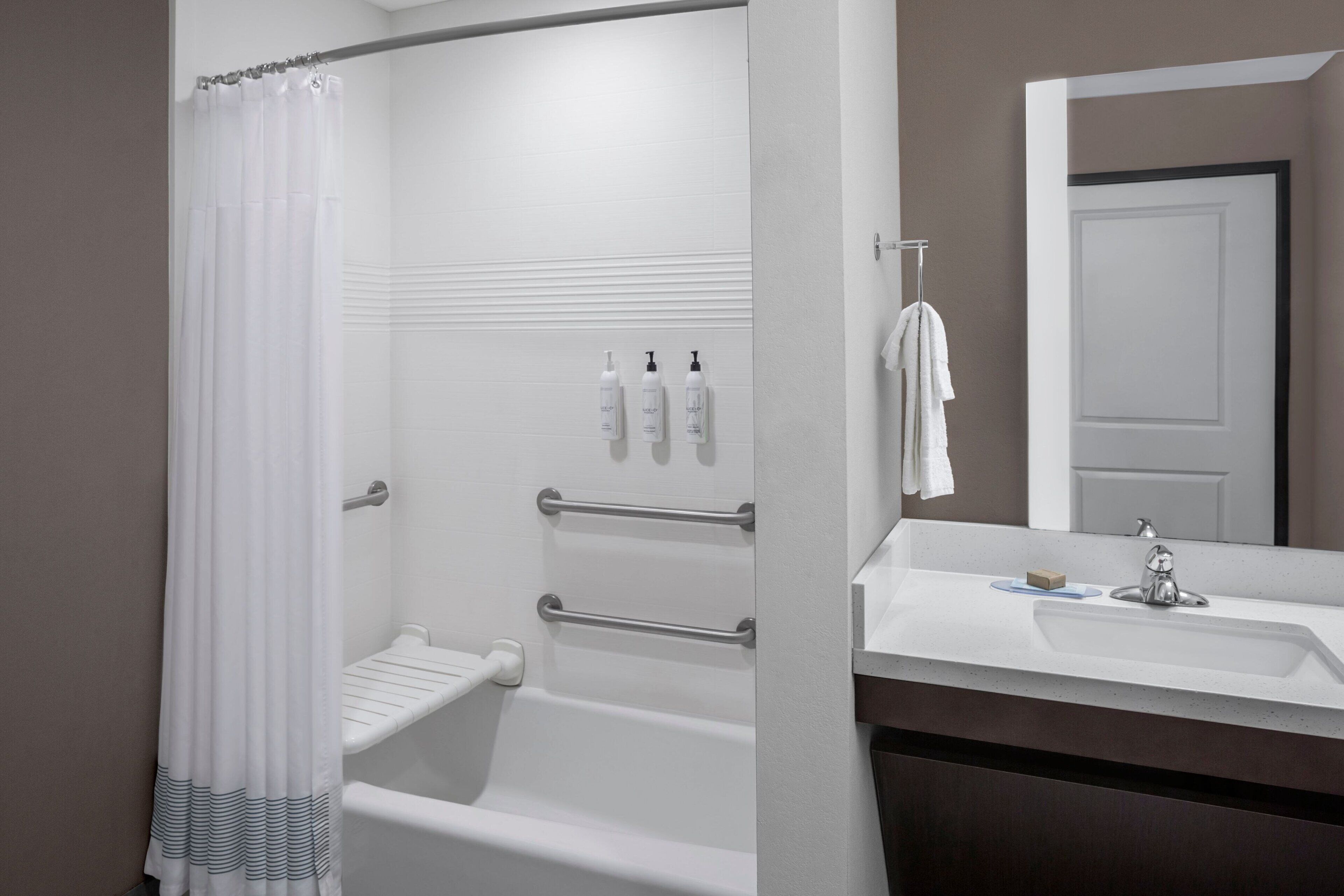A modern bathroom with a shower, a bathtub, a sink with a mirror, and toiletries on the wall.
