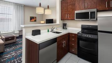 A modern kitchen with stainless steel appliances, wooden cabinets, and a white countertop.