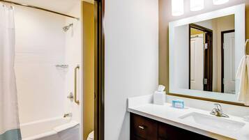 A bathroom with a bathtub, a sink, and a mirror.