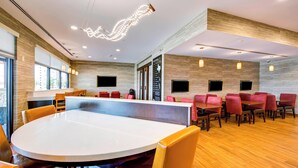 Une salle de conférence moderne dotée d’une grande table ronde, de plusieurs configurations de sièges et d’un luminaire au plafond original.