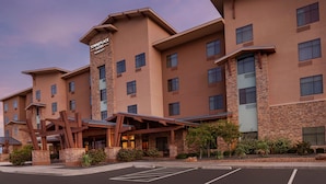 Un hôtel à plusieurs étages, doté d’une entrée imposante, d’une façade en pierre et d’une enseigne indiquant qu’il s’agit d’un hôtel TownePlace Suites Marriott.