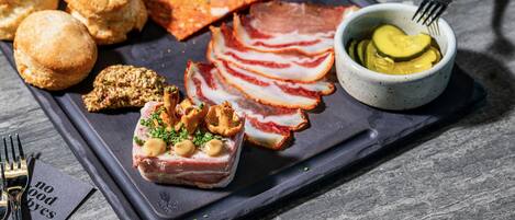 A charcuterie board with various meats, pickles, and bread.