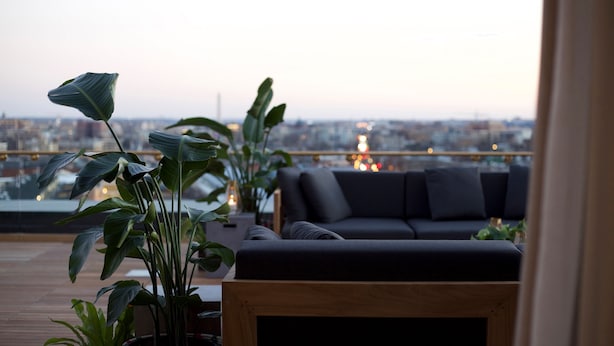 A rooftop terrace with a sofa and potted plants, overlooking a cityscape. - The LINE Hotel DC (Washington)