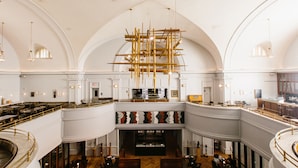 A spacious interior with a high ceiling, arched windows, and a central suspended structure. - The LINE Hotel DC (Washington)