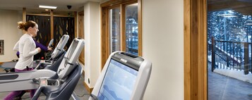 Un gimnasio con cintas de correr y un amplio ventanal con vistas a un paisaje nevado.