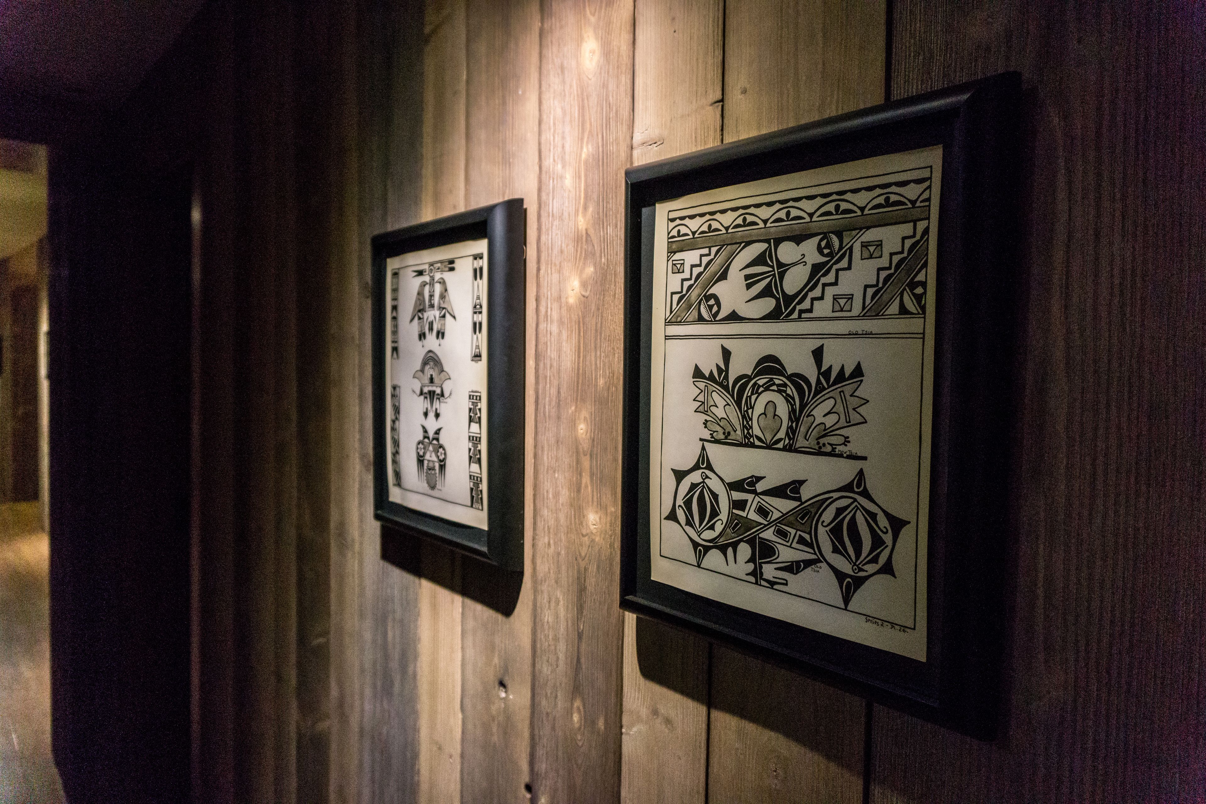 Deux œuvres d’art encadrées sont accrochées à un mur en bois.