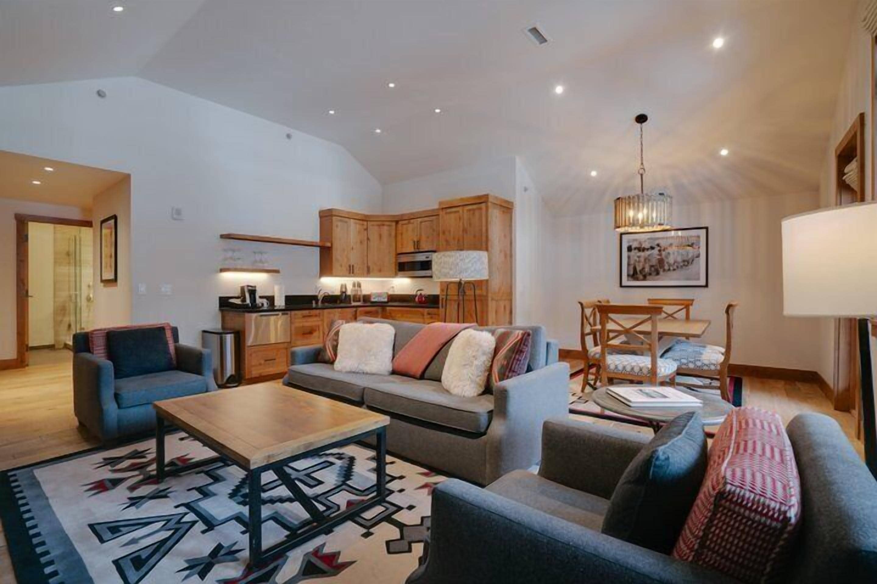 A spacious living area with a sofa set, a coffee table, and a dining area with chairs.