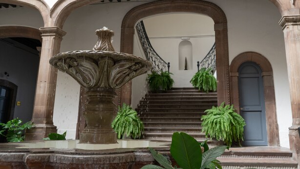 A courtyard with a fountain, a staircase, and potted plants. - Markee Hotel Boutique (Querétaro)