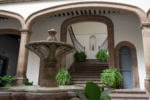 Une cour avec une fontaine, un escalier et des plantes en pot.
