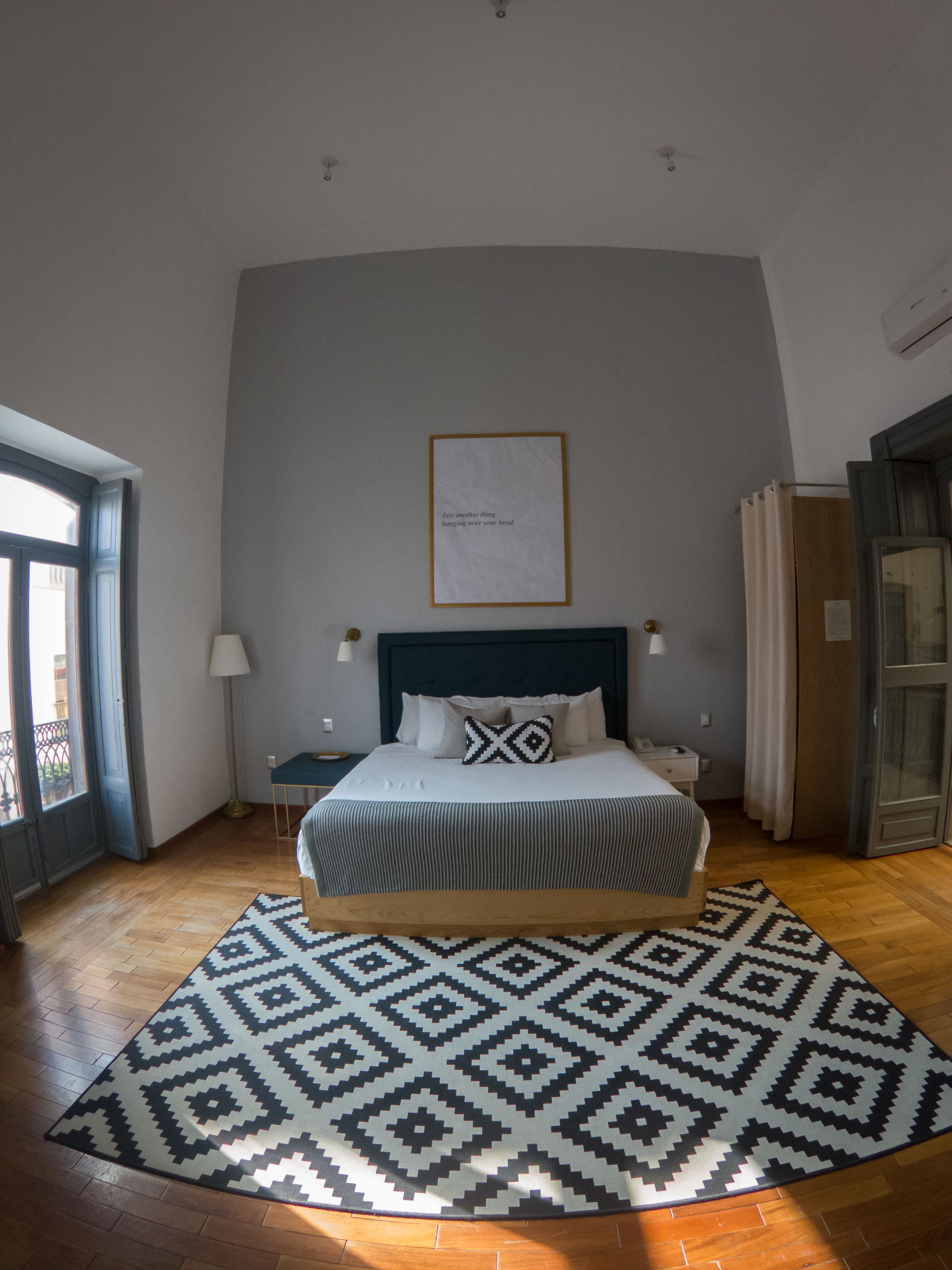 Una camera da letto con un letto, un tappeto decorato, un comodino, una lampada e un quadro appeso al muro.