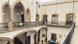 A multi-level hotel lobby with arched doorways, a reception desk, and a seating area with a sofa and coffee table. - Markee Hotel Boutique (Querétaro)