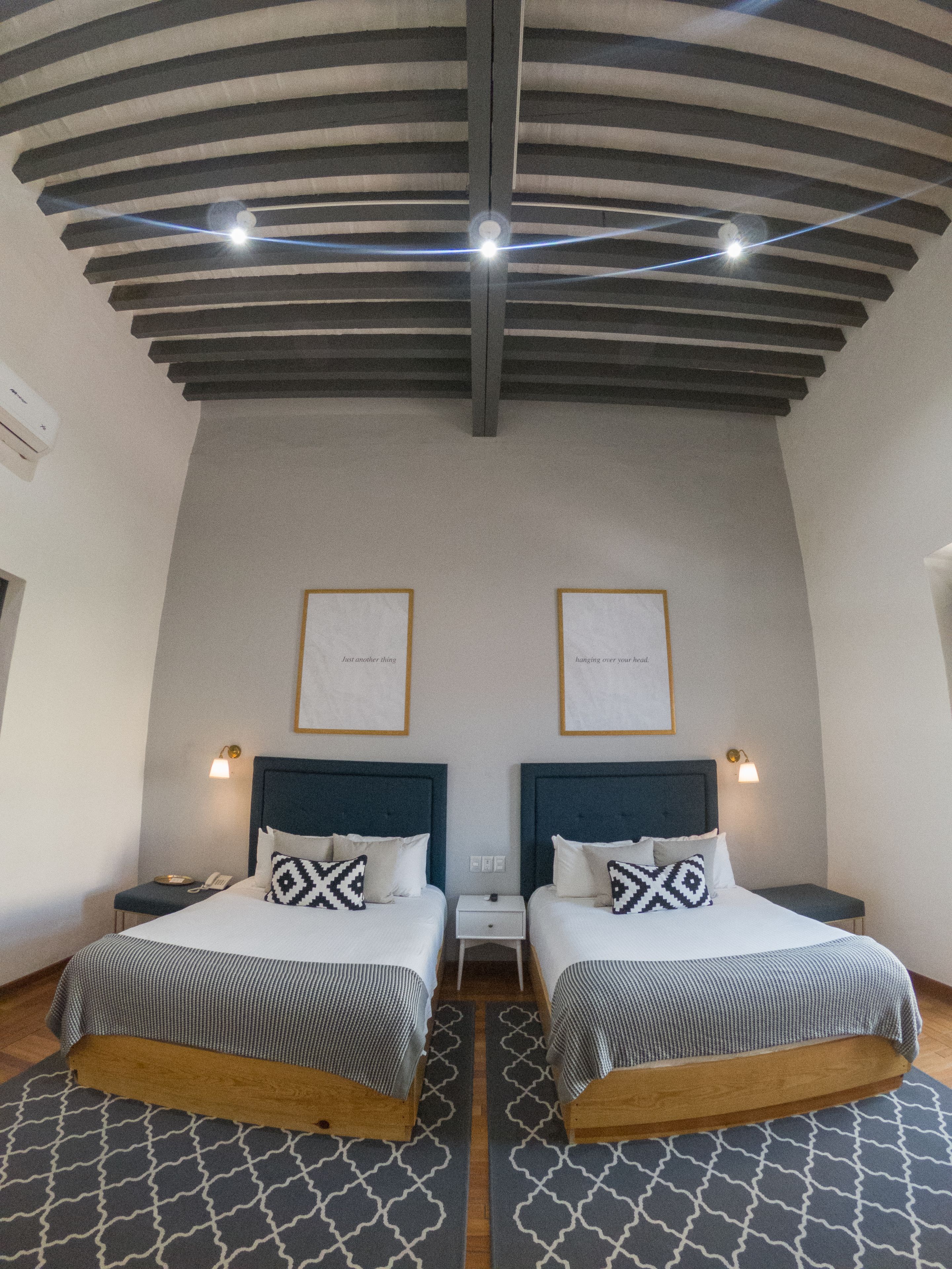 A hotel room with two beds, a wooden floor, and a sloped ceiling with exposed beams.