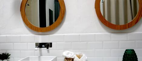 A bathroom with two wooden-framed mirrors, a white sink, and a glass countertop.