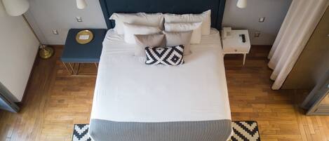 Una habitación de hotel ordenada con una cama grande, una mesita de noche y una lámpara de pie.