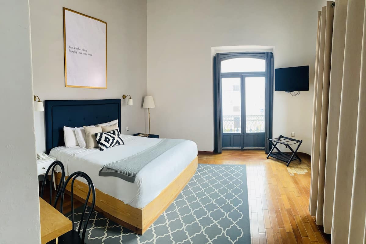 Une chambre d’hôtel équipée d’un lit, d’une table de chevet, d’une lampe, d’une télévision et offrant une vue sur l’extérieur.