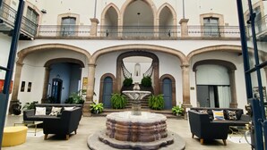 A spacious courtyard with a central fountain, surrounded by arches and balconies. - Markee Hotel Boutique (Querétaro)