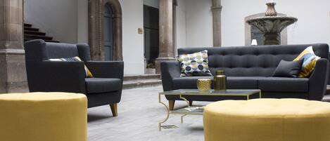 Um interior moderno com dois sofás, uma mesa de centro e pufes amarelos.