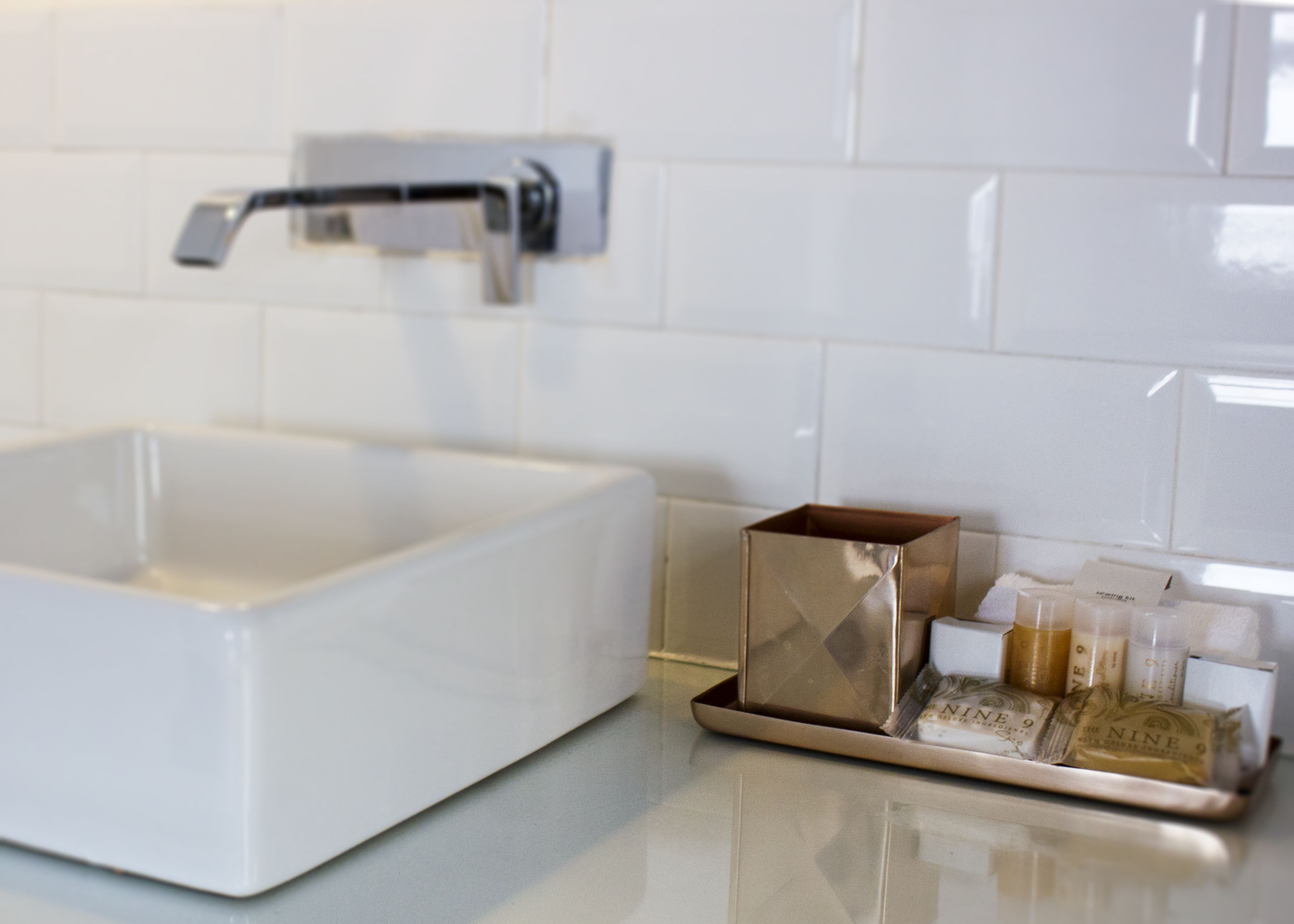 Uma casa de banho moderna com uma pia branca, uma torneira e um porta-produtos.