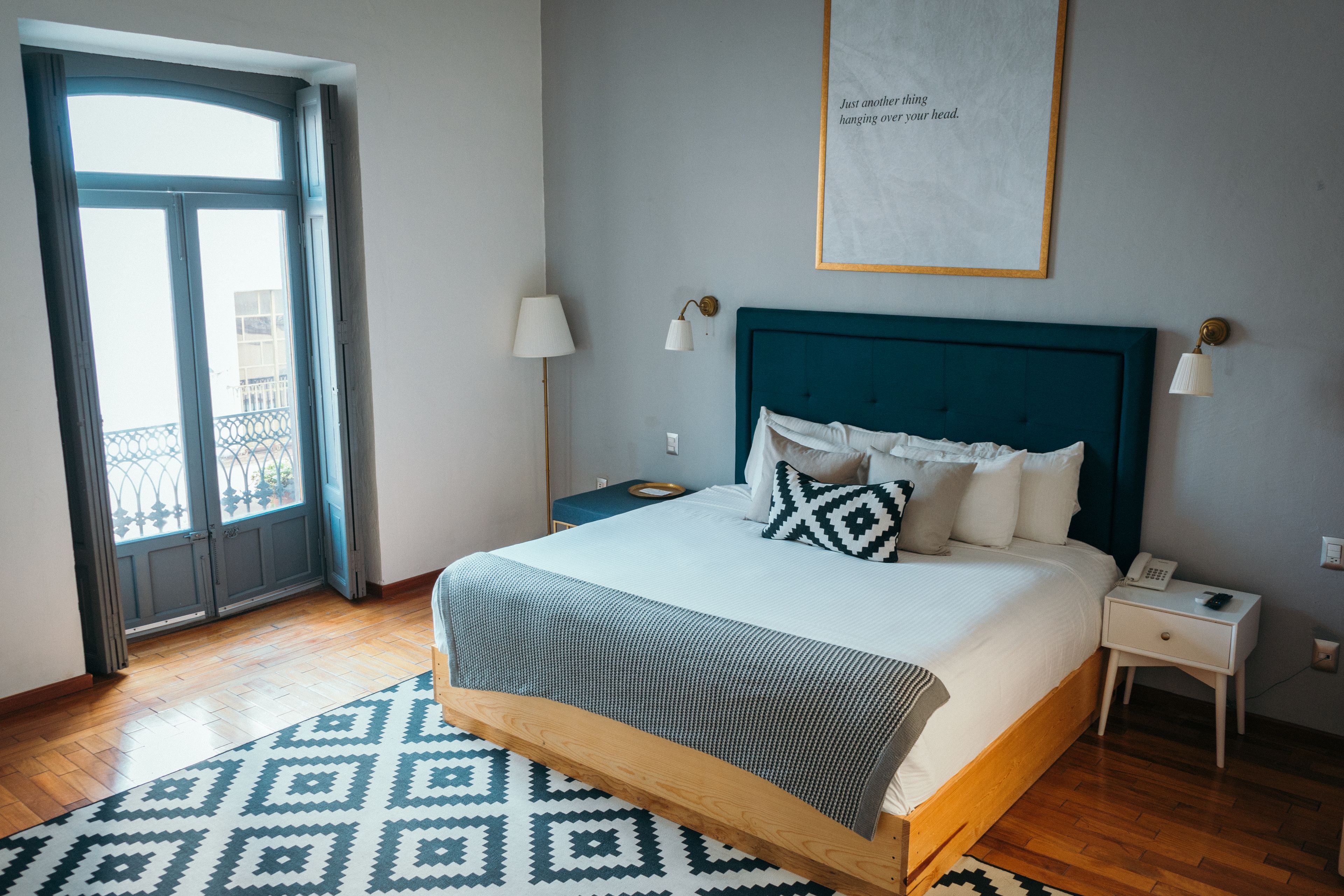 A neatly arranged bedroom with a bed, bedside tables, a lamp, and a framed quote on the wall.