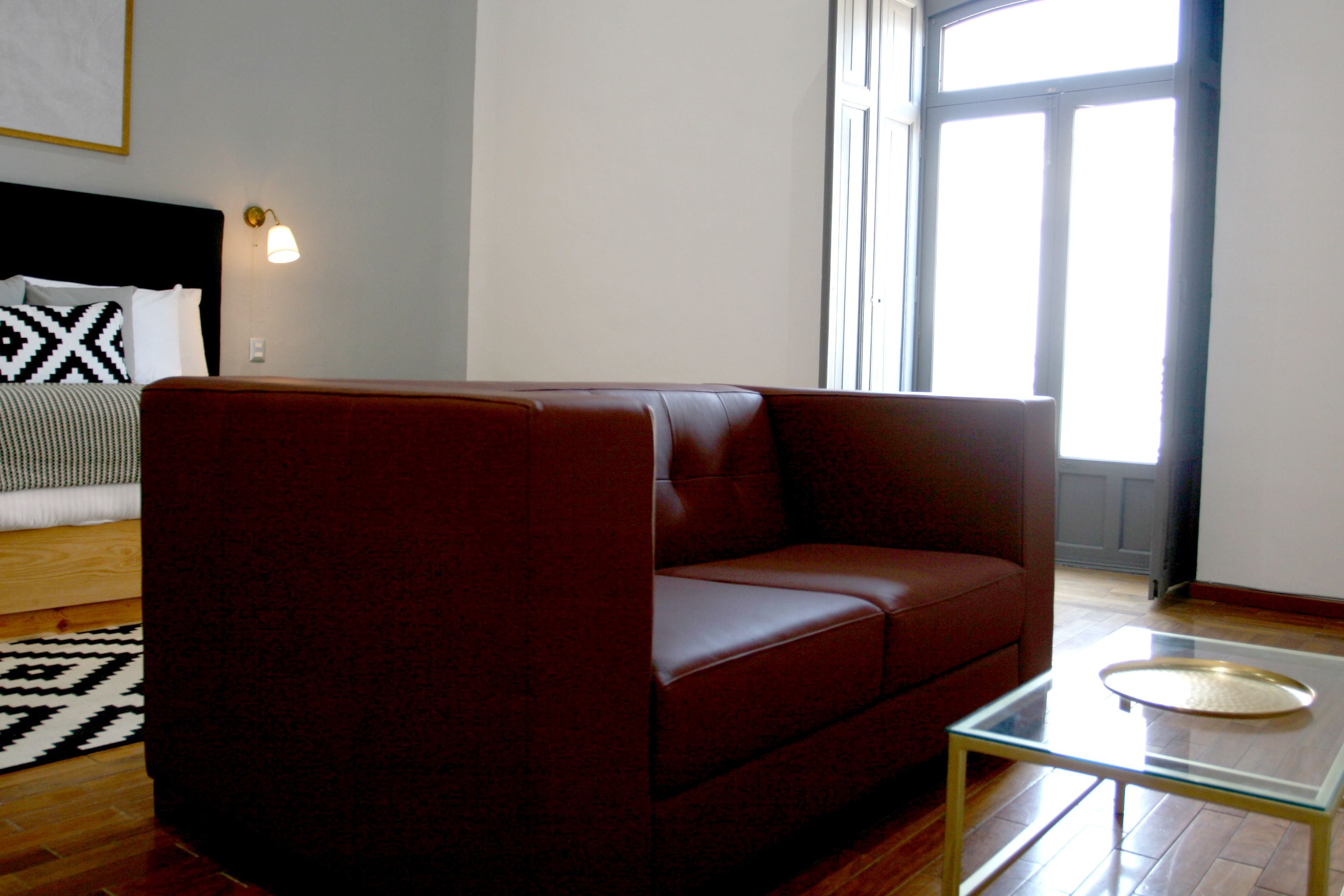 Uma sala de estar moderna com um sofá de couro, uma mesa de centro de vidro e um tapete estampado.