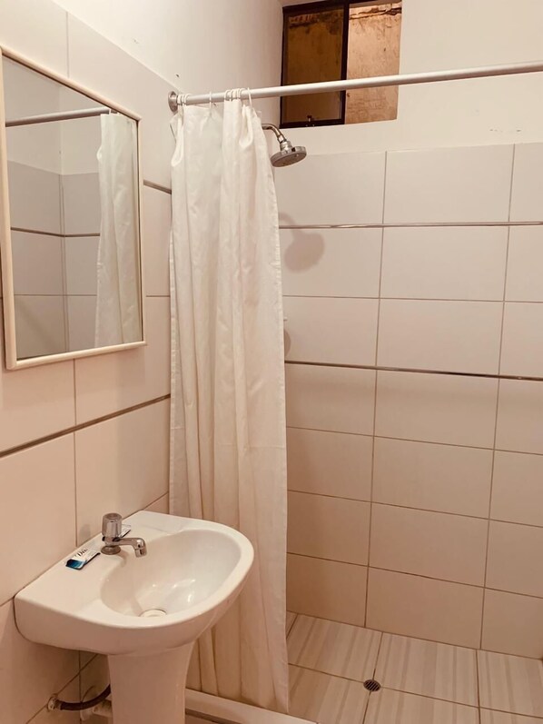 A bathroom with a white sink, a mirror, a shower curtain, and tiled walls.