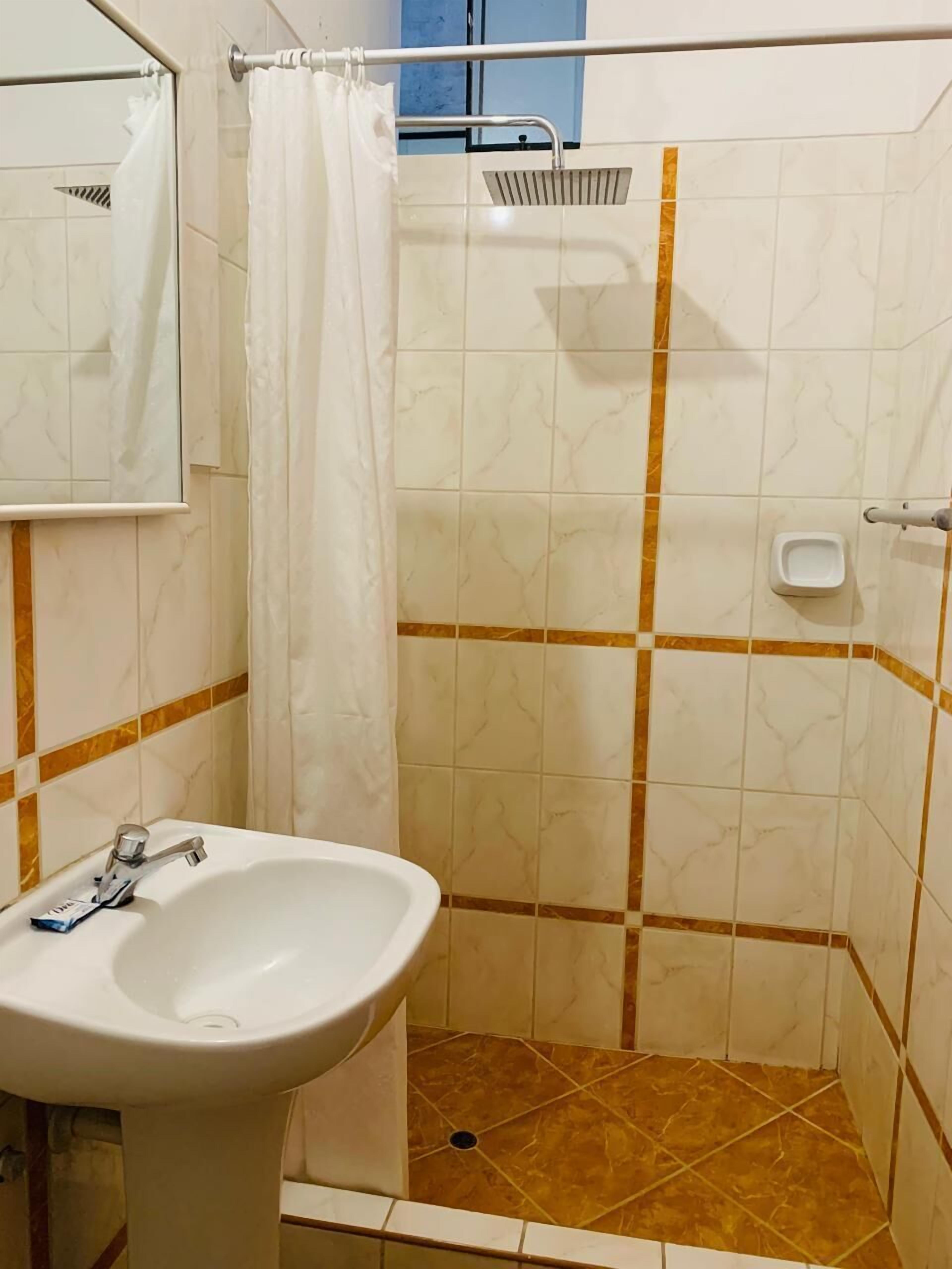 A bathroom with a shower, a sink, and a mirror.