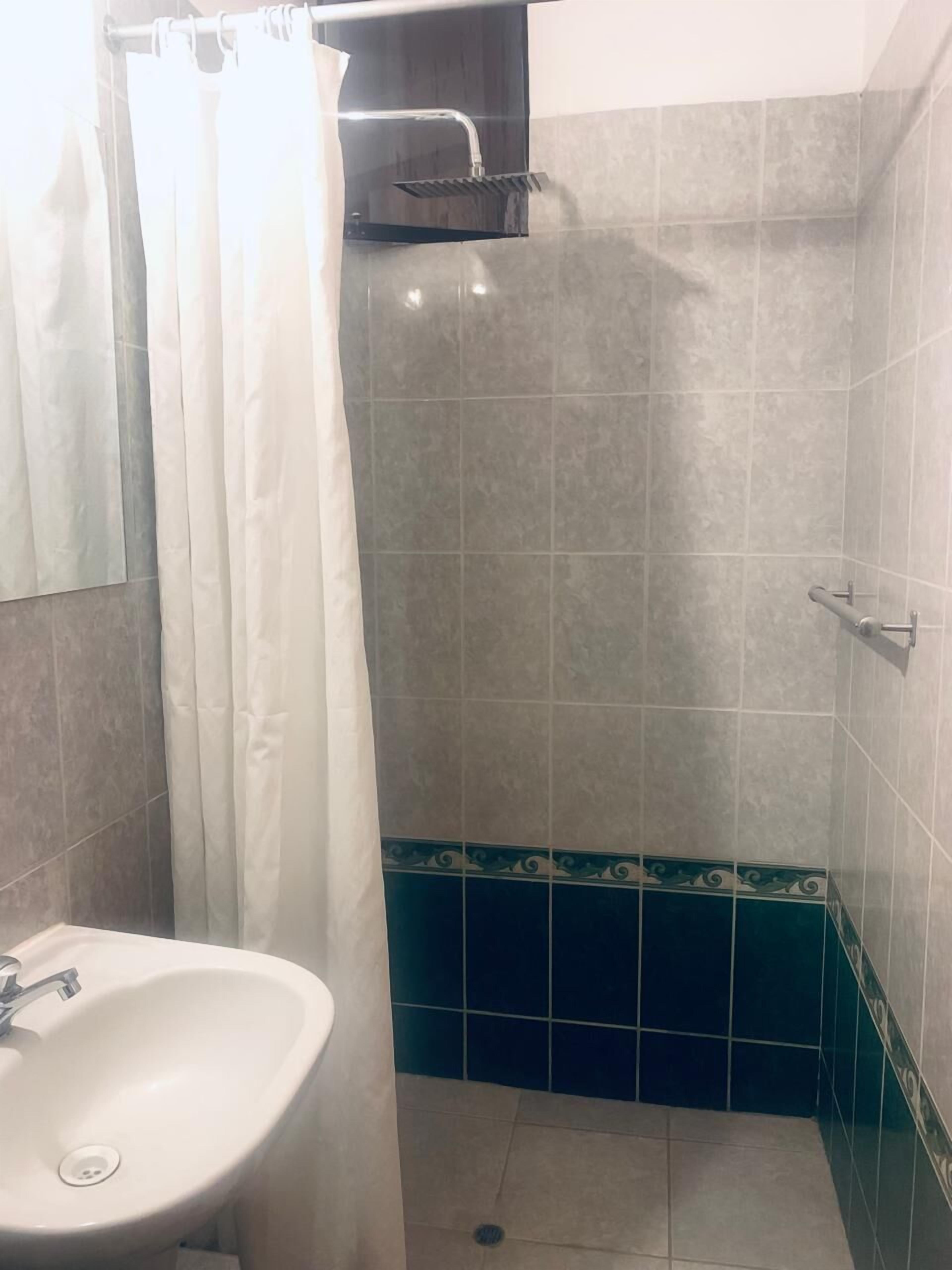 A bathroom with a shower, a sink, and tiled walls.